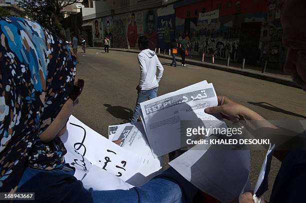 An Egyptian woman distributes a sheet of Tamarod campaign try to collect signatures to demand the ouster of Egyptian President Mohamed Morsi and for...