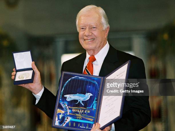 Former U.S. President Jimmy Carter holds up his Nobel Peace Prize December 10, 2002 in Oslo, Norway. Carter was recognized for many years of public...
