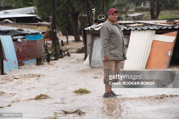 Man stands on mud brought there by a mudslide and heavy flooding as a result of a storm, close to his home, in Sir Lowry's Village, close to Somerset...