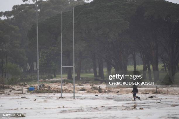 Man walks across the village rugby field during heavy flooding as a result of a storm in Sir Lowry's Village, close to Somerset West on September 25,...