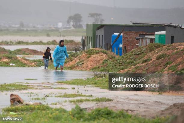 Woman and child walks through water and mud during heavy flooding as a result of a storm in Sandvlei, close to Somerset West on September 25, 2023.