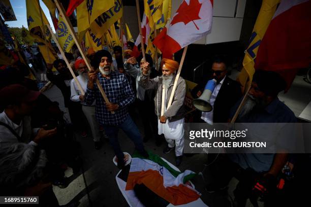 People stomp on an Indian flag and a cutout of Indian prime minister Narendra Modi during a Sikh rally outside the Indian consulate in Toronto to...