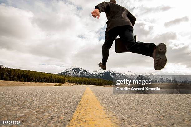 businessman in mid-air stride above mtn road - businessman running stock pictures, royalty-free photos & images