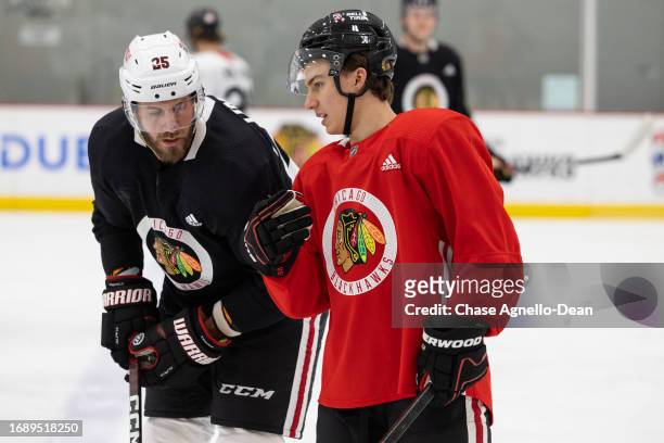 Jarred Tinordi of the Chicago Blackhawks talks with Connor Bedard of the Chicago Blackhawks during practice at Fifth Third Arena on September 25,...