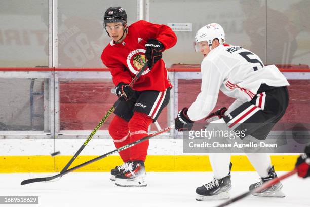 Connor Bedard of the Chicago Blackhawks passes the puck over the stick of Connor Murphy of the Chicago Blackhawks during a scrimmage at Fifth Third...