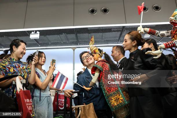Visitors pose for photographs during an event to welcome inbound tourists from China at Suvarnabhumi Airport in Bangkok, Thailand, on Monday, Sept....