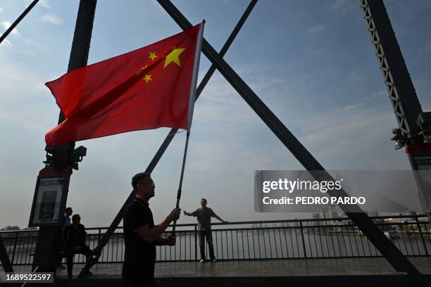 This picture taken on September 22, 2023 shows a man carrying a Chinese flag while visiting the Broken bridge, which once spanned the Yalu River...