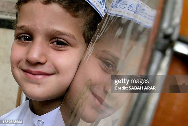 The face of eight-year old Iraqi boy Abdullah is reflected on a tambourine at Sunni Muslim Abu Hanifa mosque in central Baghdad 21 April 2005 as he...