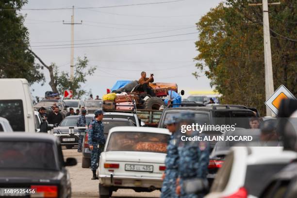 Armenian police officers walks near refugees as they queue in vehicles near the border town of Kornidzor, arriving from Nagorno-Karabakh, on...