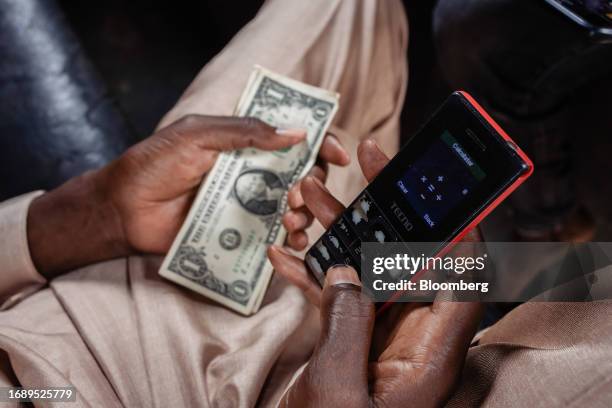 Street currency dealer uses a smartphone calculator app to calculate the rate for exchanging US dollar banknotes at a market in Lagos, Nigeria, on...