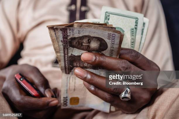 Street currency dealer holds US dollar banknotes and Nigerian naira banknotes at a market in Lagos, Nigeria, on Monday, Sept. 25, 2023. The Nigerian...