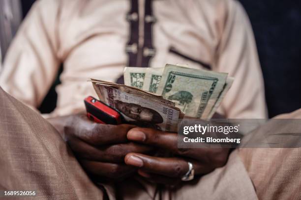 Street currency dealer holds US dollar banknotes and Nigerian naira banknotes at a market in Lagos, Nigeria, on Monday, Sept. 25, 2023. The Nigerian...