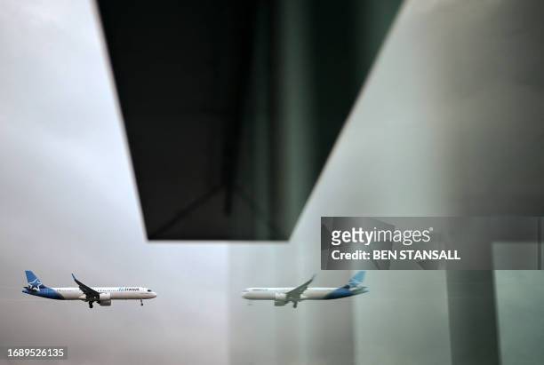 An Air Transat Airbus 321 aircraft is reflected in a window as it prepares to land at London Gatwick Airport, near Crawley, southern England, on...