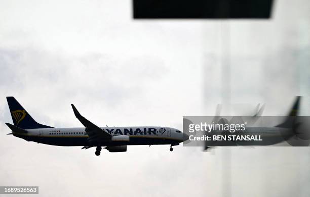 Ryanair Boeing 737-8AS aircraft is reflected in a window as it prepares to land at London Gatwick Airport, near Crawley, southern England, on...