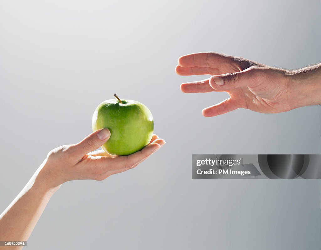 Woman handing man an apple