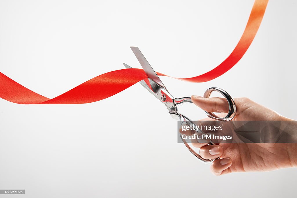 Hand cutting red ribbon with scissors