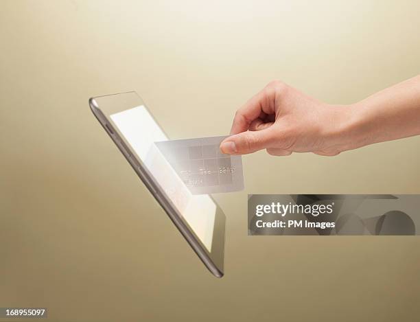 hand placing credit card into tablet - fotografia da studio fotografías e imágenes de stock