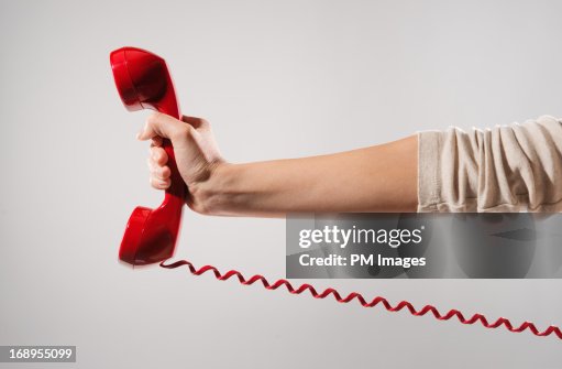 Woman's hand holding red phone Woman's hand holding red phone