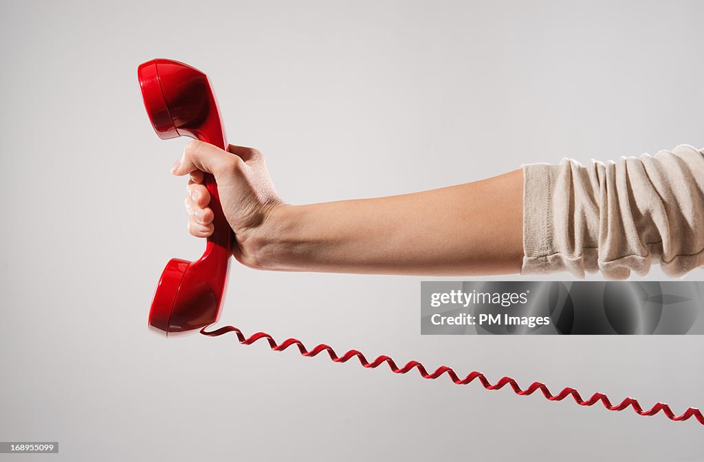 Woman's hand holding red phone