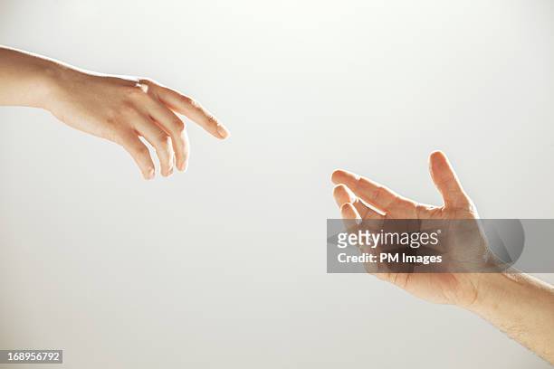 hands reaching towards each other - two hands stock-fotos und bilder