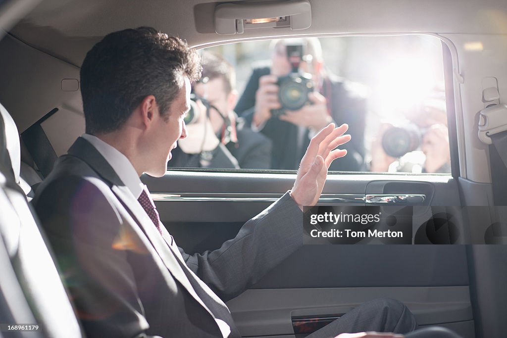 Politician waving from backseat of car