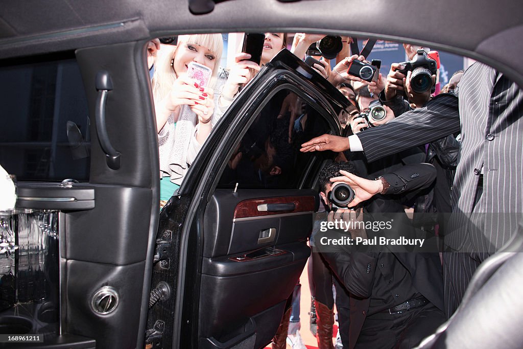 Paparazzi and fans taking photos inside car door