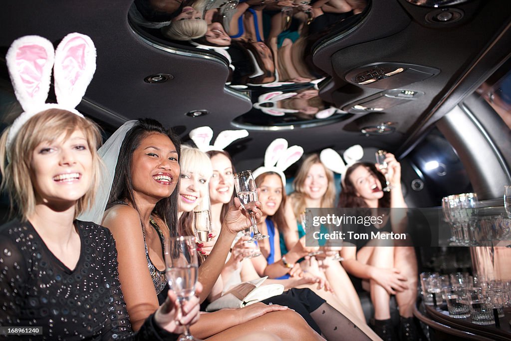 Women in bunny ears toasting in back of limo