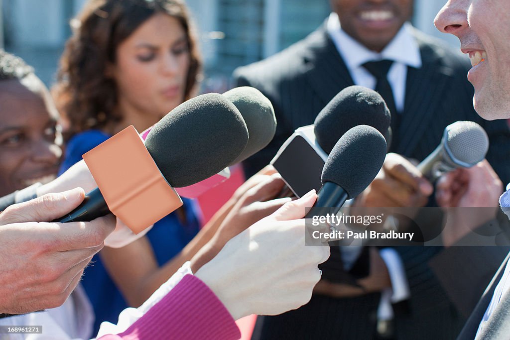 Politician talking into reporters' microphones