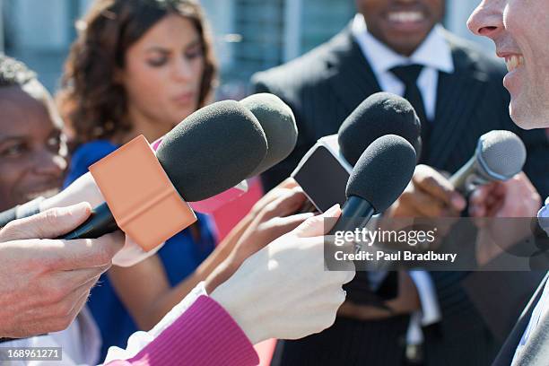 politician talking into reporters' microphones - corporate news bildbanksfoton och bilder