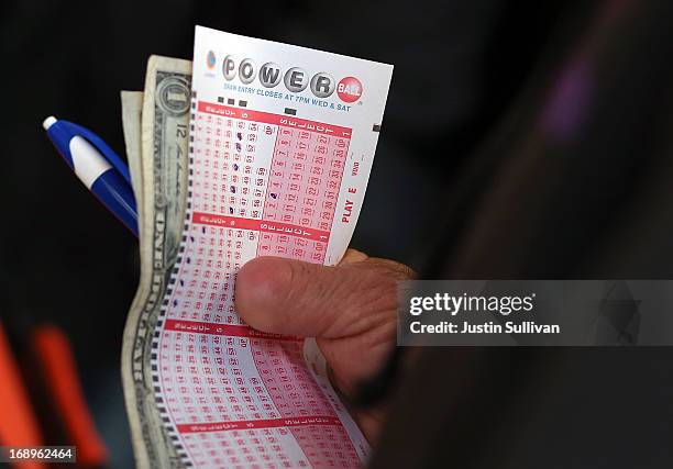 Customer holds a Powerball ticket and money as he waits in line on May 17, 2013 in San Francisco, California. People are lining up to purchase $2...