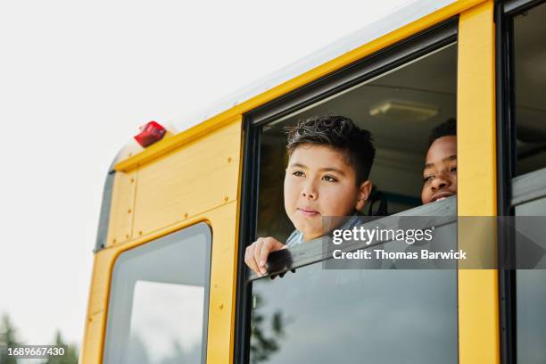 medium shot middle school boy looking out open window of school bus - open day 13 stock pictures, royalty-free photos & images