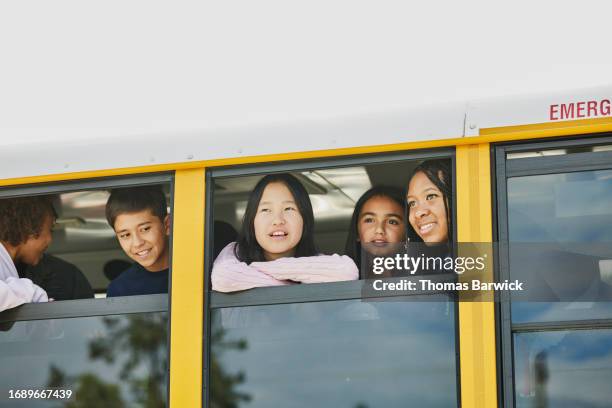 medium shot middle school students looking out windows of school bus - open day 13 stock pictures, royalty-free photos & images