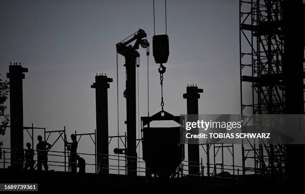 Construction workers are silhouetted against the sky at a construction site in Berlin on September 26, 2023. German business sentiment fell less than...