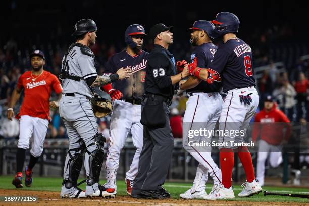 Dominic Smith of the Washington Nationals is held back by Carter Kieboom and umpire Will Little after an exchange with Mike Clevinger of the Chicago...