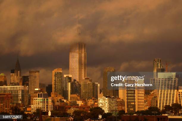 The sun sets on the skyline of midtown Manhattan and the Empire State Building as rain clouds clear out of New York City on September 18 as seen from...