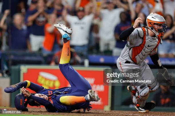 Mauricio Dubon of the Houston Astros is safe at home ahead of Adley Rutschman of the Baltimore Orioles during the sixth inning at Minute Maid Park on...