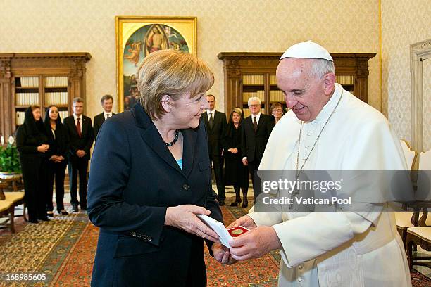 Chancellor of Germany Angela Merkel exchanges gifts with Pope Francis during an audience at his private library on May 18, 2013 in Vatican City,...