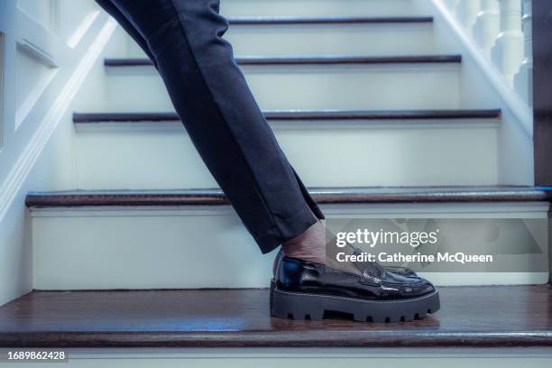 black woman standing on stairs wearing black pants & black loafers - leather trousers stock-fotos und bilder