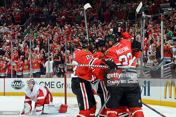 Johnny Oduya and Michal Rozsival of the Chicago Blackhawks hug teammate Patrick Kane after Kane scored in the first period, as goalie Jimmy Howard of...