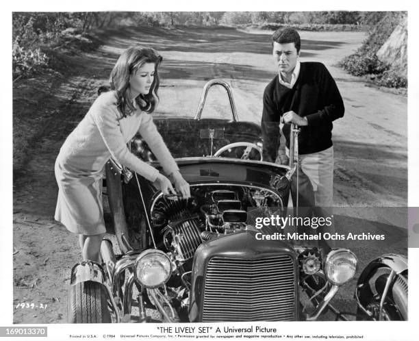 Pamela Tiffin and James Darren dealing with car issues on the side of the road in a scene from the film 'The Lively Set', 1964.