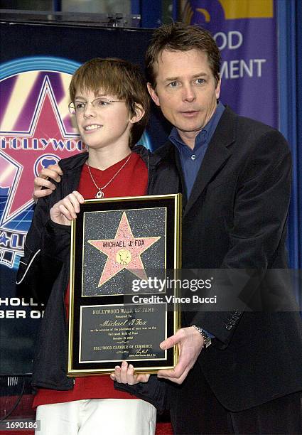 Actor Michael J. Fox and son Sam pose with a replica of the star Fox received at the ceremony honoring him on the Hollywood Walk of Fame on December...