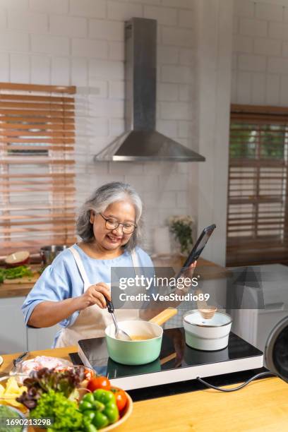 asian senior woman cooking food in the kitchen. - cookbook stock pictures, royalty-free photos & images