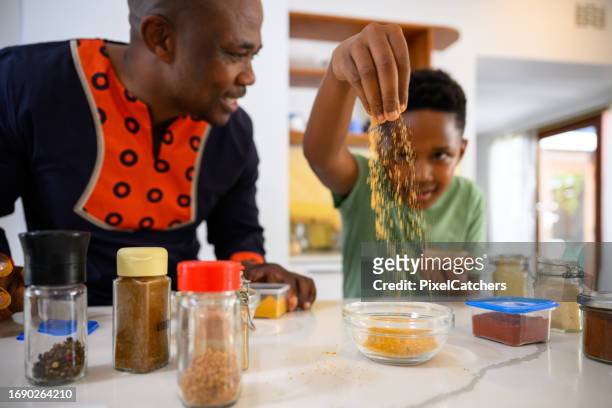 spices sprinkle from fingers father and son preparing food together - adding spice stock pictures, royalty-free photos & images