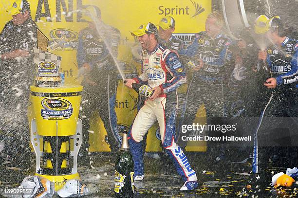 Jimmie Johnson, driver of the Lowe's Patriotic Chevrolet, celebrates with champagne in Victory Lane after winning the NASCAR Sprint Cup Series...