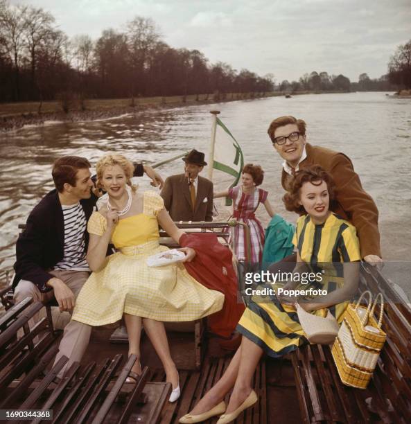 Group of men and women standing and seated on the top deck of a boat as it cruises down the River Thames at Richmond in southwest London on 4th June...