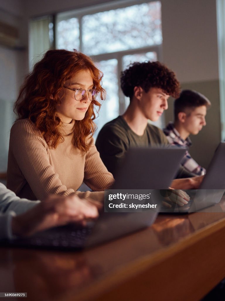 Les élèves du secondaire apprennent en ligne sur des ordinateurs en classe.