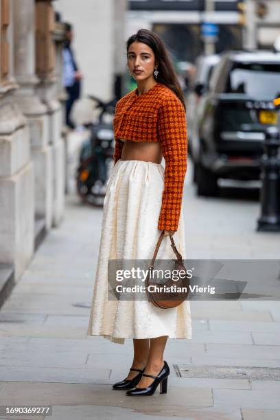 Bettina Looney wears cropped checkered top, creme white skirt, bag outside Emilia Wickstead during London Fashion Week September 2023 at the on...