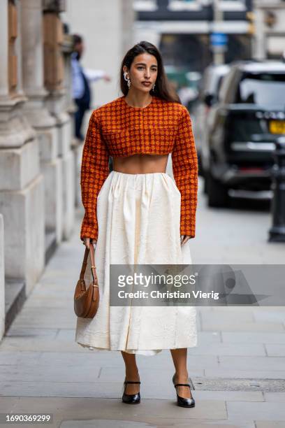 Bettina Looney wears cropped checkered top, creme white skirt, bag outside Emilia Wickstead during London Fashion Week September 2023 at the on...