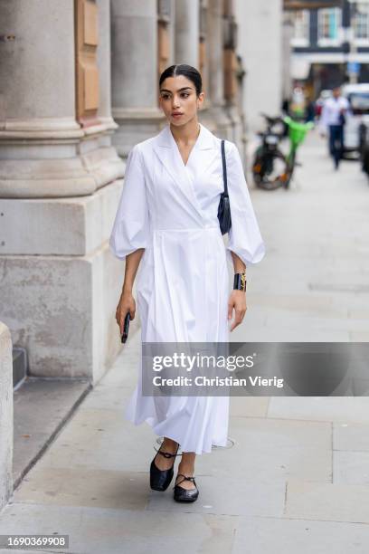 Guest wears white dress, black bag, shoes outside Emilia Wickstead during London Fashion Week September 2023 at the on September 18, 2023 in London,...