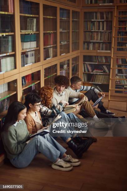 group of students reading books on floor in library. - student reading book stockfoto's en -beelden